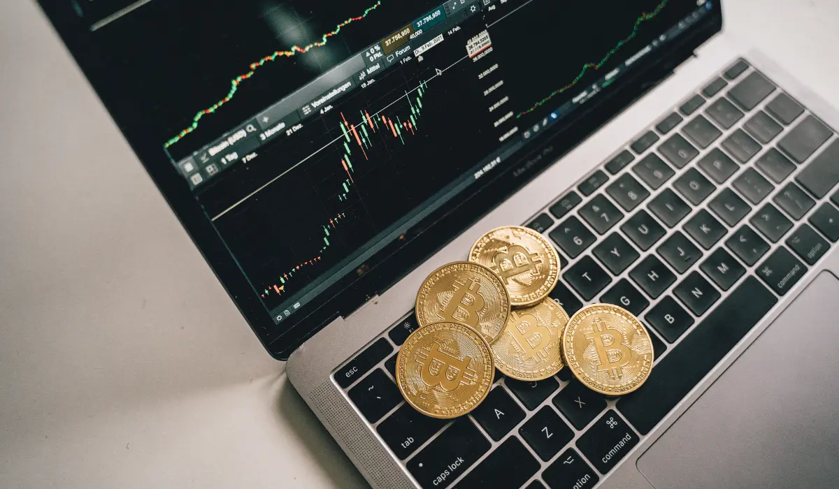 Bitcoin coins on laptop with crypto trading chart